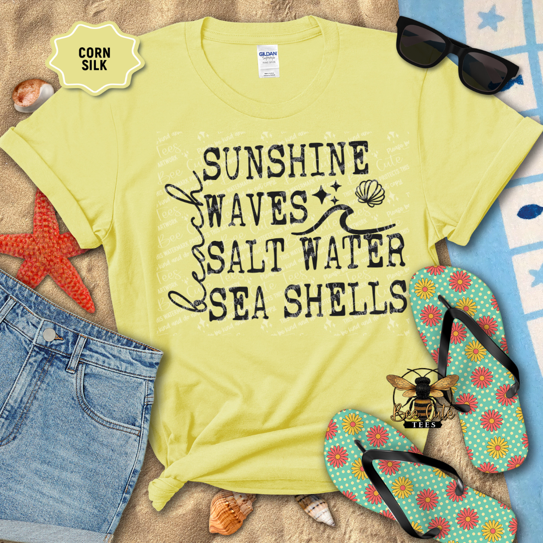 Yellow t-shirt with beach-themed text on a sandy background with flip-flops and sunglasses.