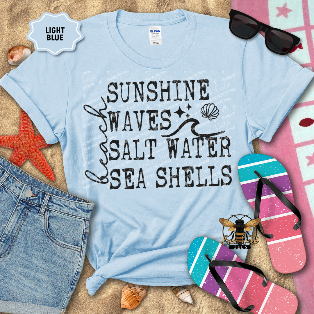 Light blue t-shirt with 'Sunshine Waves Salt Water Sea Shells' text, surrounded by beach-themed items.