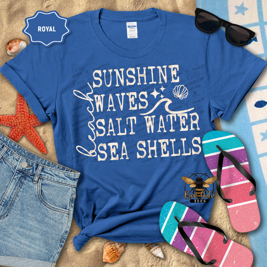 Blue t-shirt with 'Sunshine Waves Salt Water Sea Shells' text, sunglasses, and flip-flops on a beach-themed background.