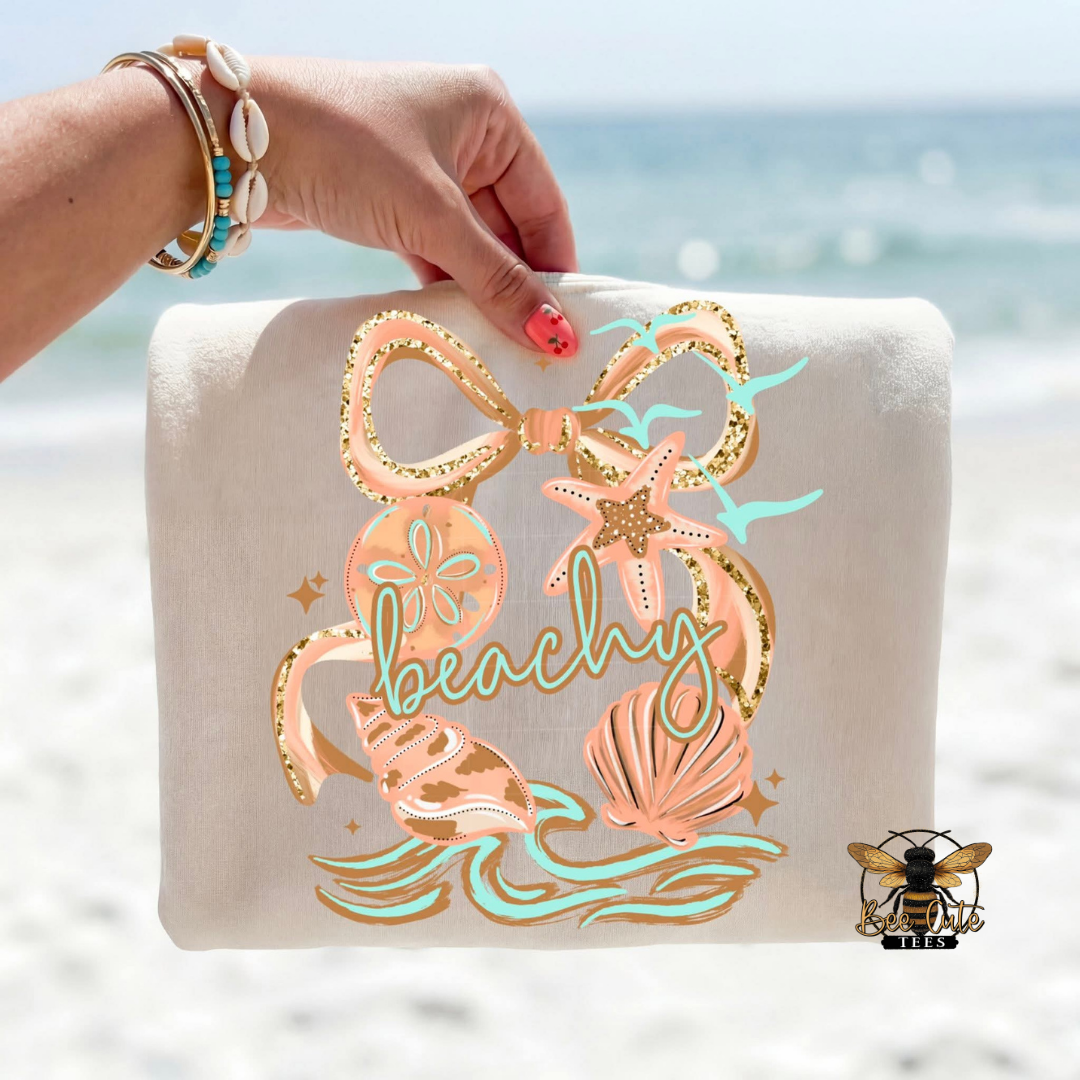 Beach-themed pouch with decorative elements and 'beachy' text held by a hand against a beach background.