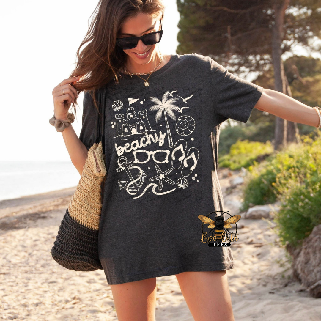 Woman wearing a black t-shirt with beach-themed graphics on a beach.