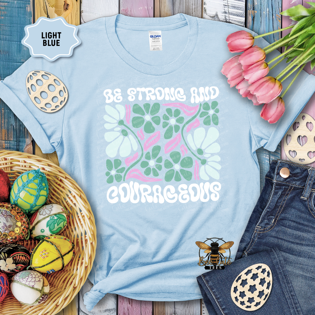 Light blue t-shirt with floral design and text, surrounded by Easter decorations on a wooden surface.
