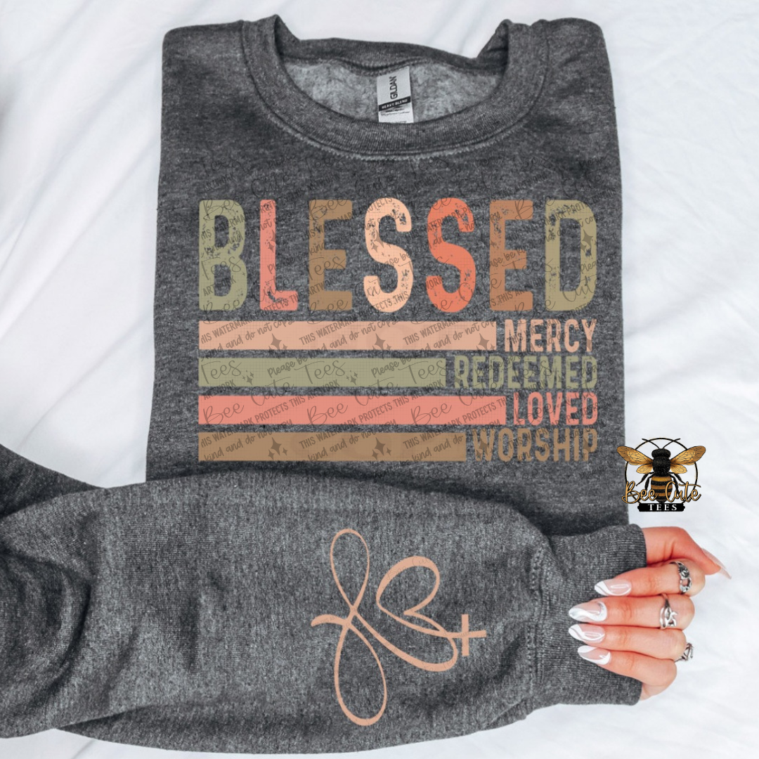 Gray sweatshirt with 'BLESSED' text design held by a hand on a white background
