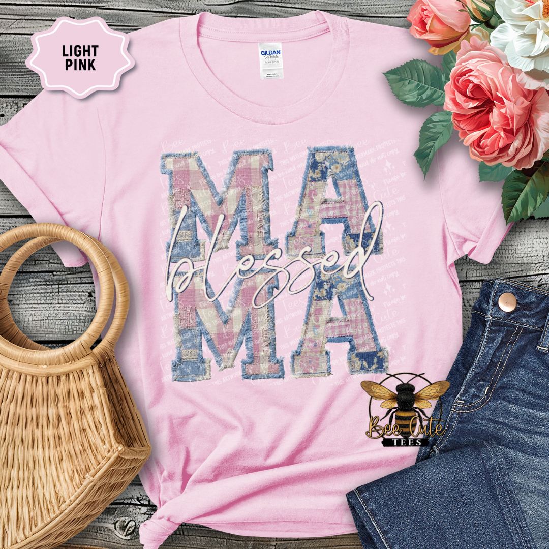 Light pink t-shirt with 'MAMA blessed' design on a wooden surface with flowers and denim jeans.