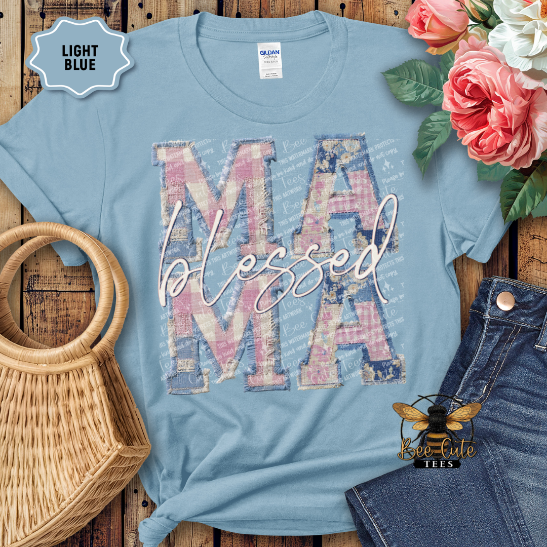 Light blue t-shirt with 'MAMA blessed' design on a wooden surface with flowers and jeans.