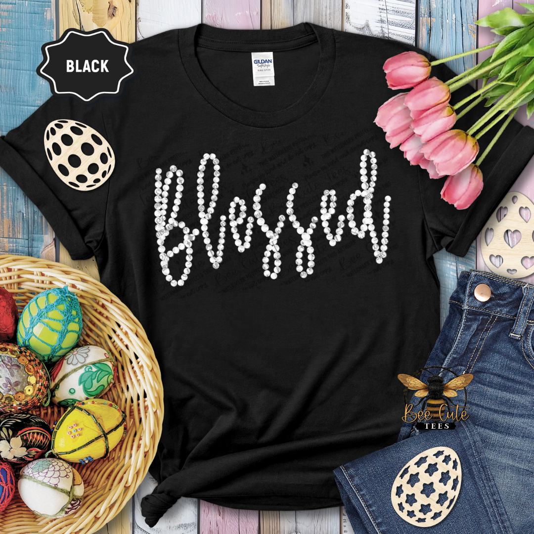 Black t-shirt with 'Blessed' text, surrounded by Easter decorations on a wooden surface.