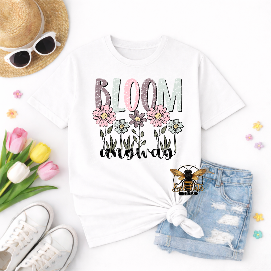 White t-shirt with 'Bloom Now' design, sunglasses, tulips, and denim shorts on a white background