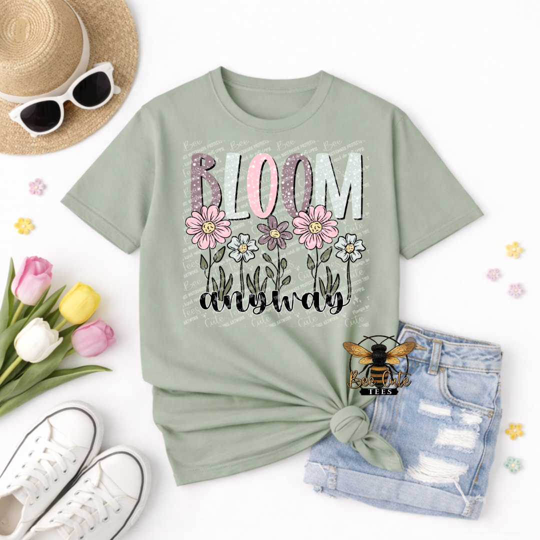 Mint green t-shirt with 'Bloom Anyway' text and flowers, surrounded by sunglasses, tulips, and denim shorts on a white background.