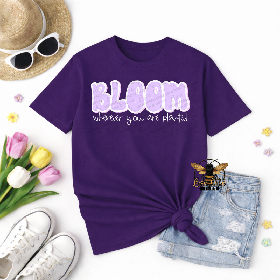 Purple t-shirt with 'Bloom wherever you are planted' text, sunglasses, tulips, and denim shorts on a white background.