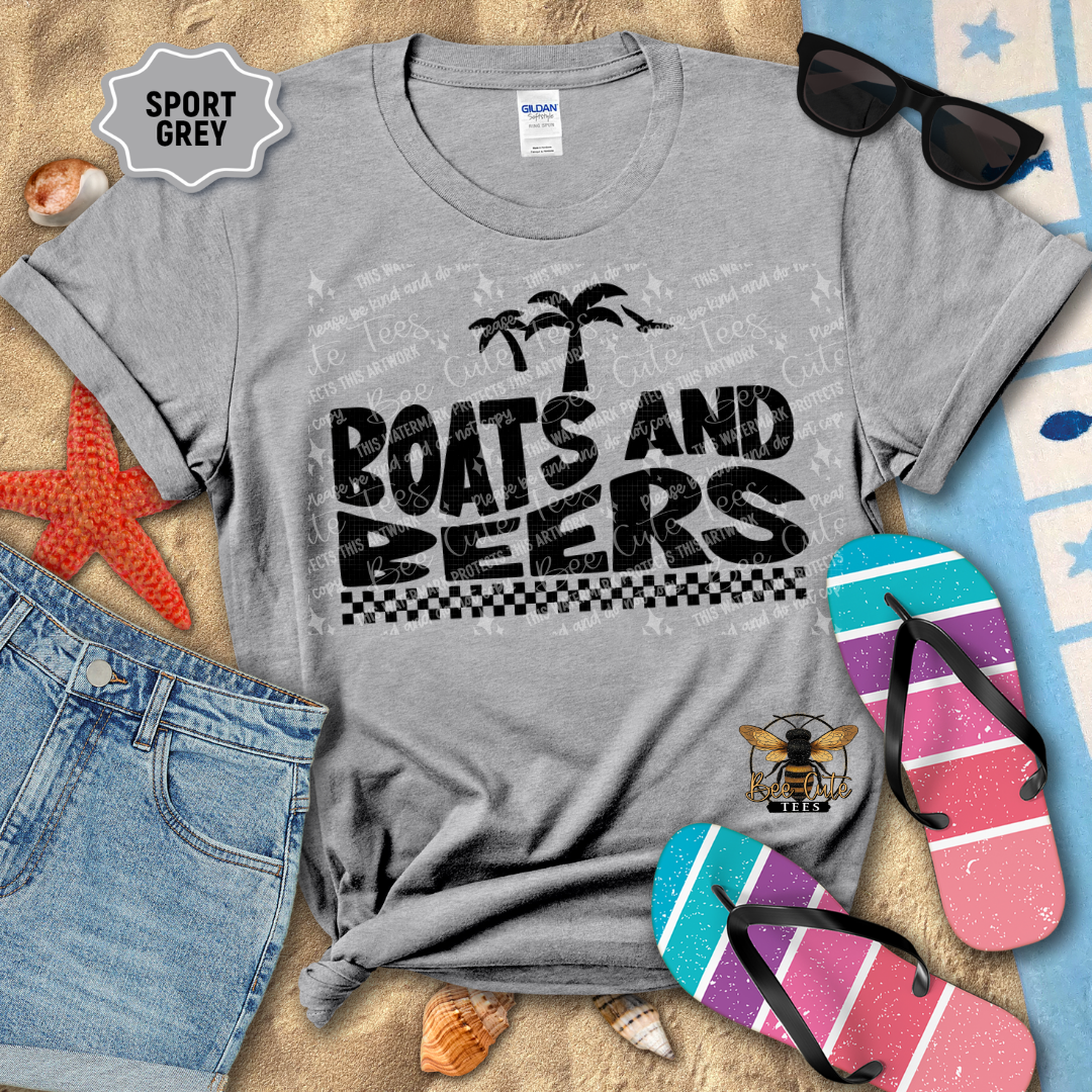 Gray t-shirt with 'Boats and Beers' text and palm trees, surrounded by beach accessories on sand.