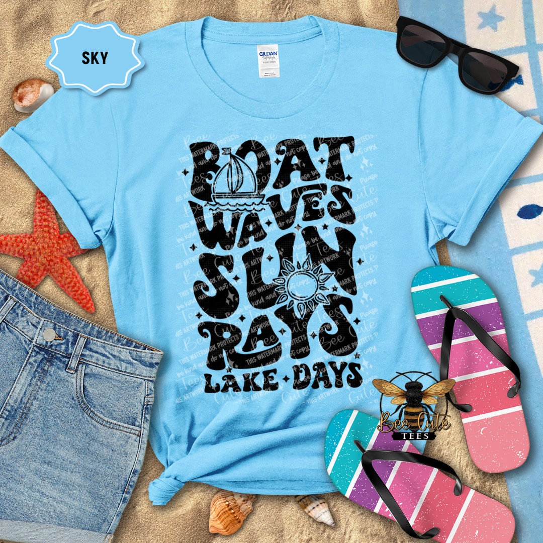 Light blue t-shirt with beach-themed design and accessories on a sandy background