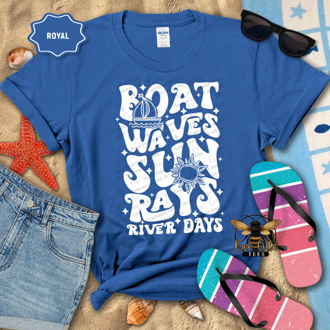 Blue t-shirt with 'Boat Waves Sun Rays River Days' design, sunglasses, flip-flops, and denim shorts on a beach-themed background.