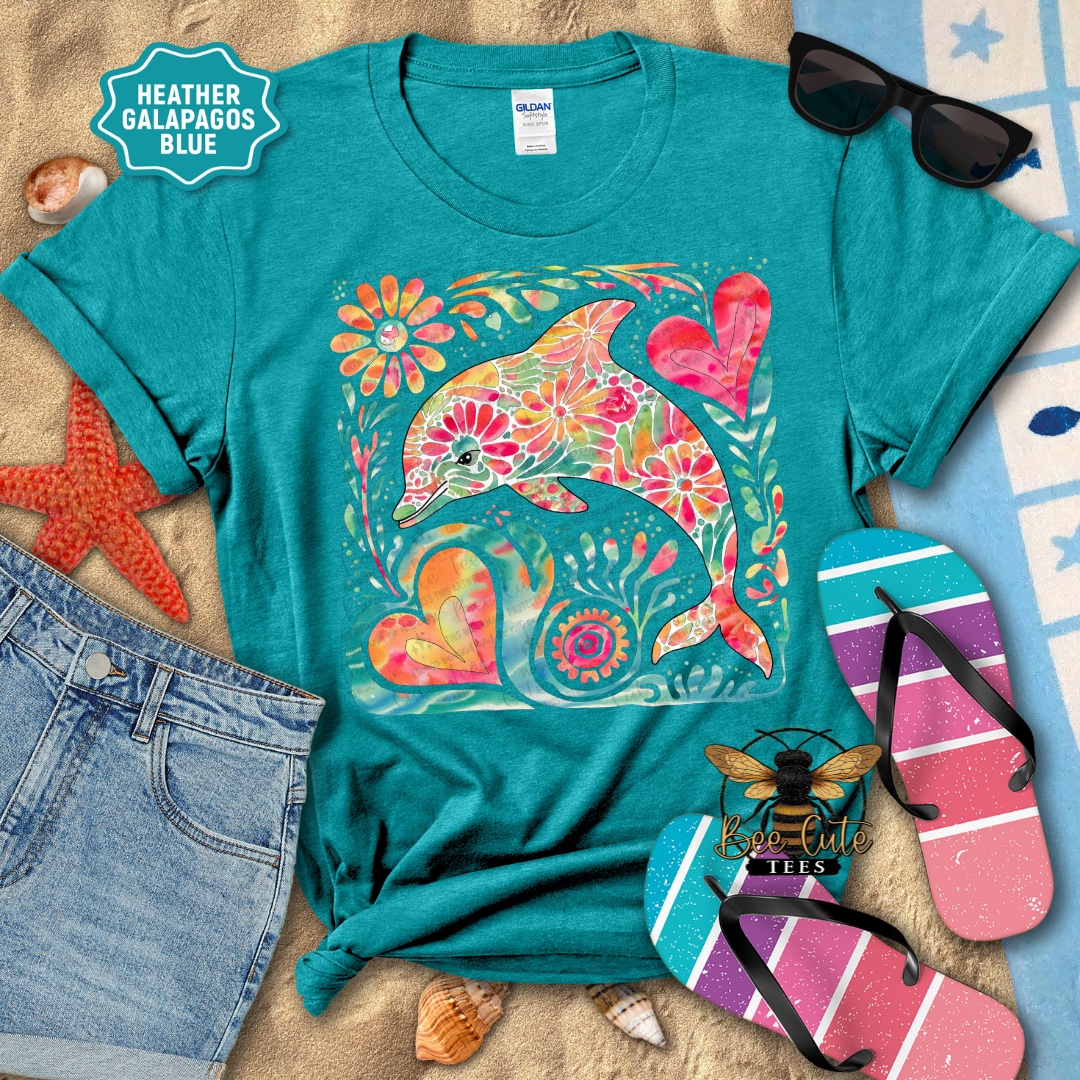 Teal t-shirt with colorful dolphin design on a beach-themed background