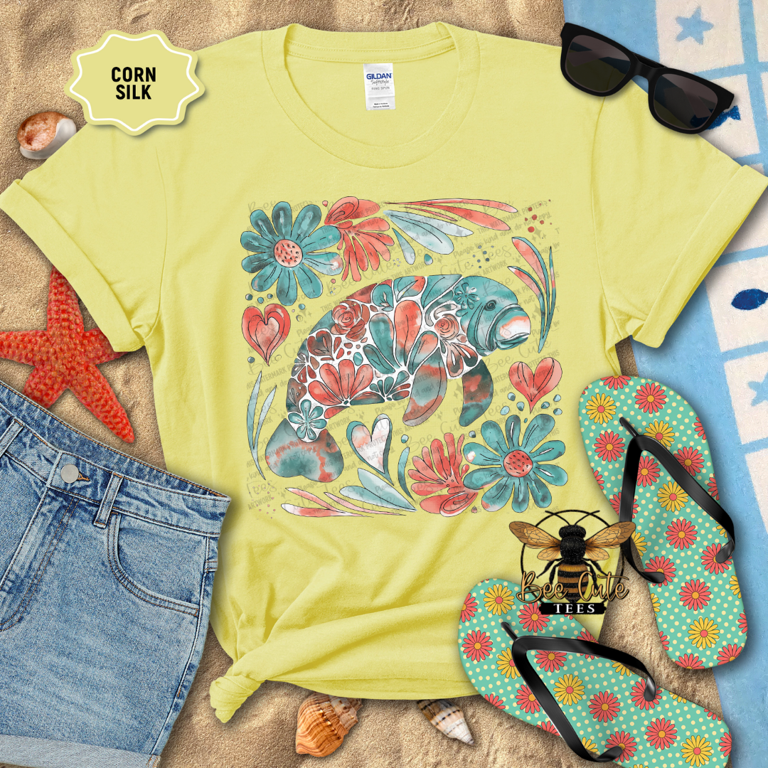 Yellow t-shirt with floral manatee design, sunglasses, and flip-flops on a beach-themed background.