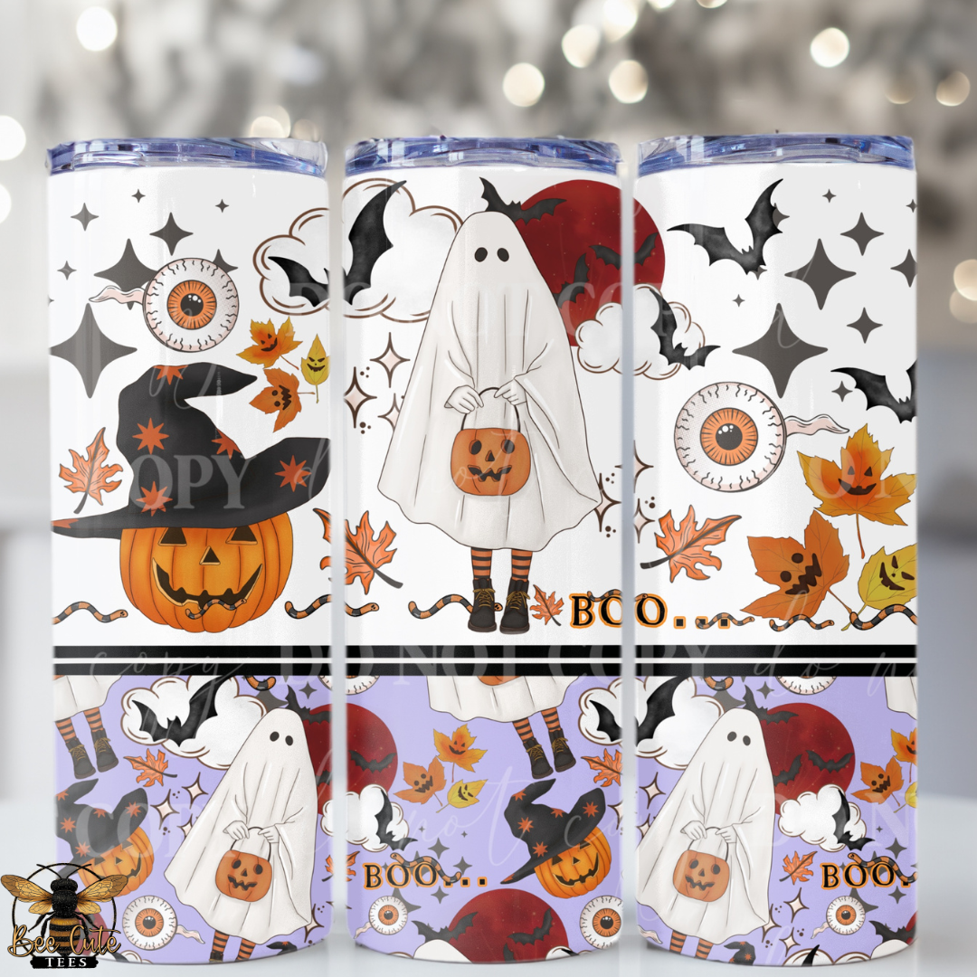 Three tall skinny tumblers with a Halloween-themed print, shown side-by-side against a blurred bokeh background. The design features cartoon ghosts, pumpkins, bats, stars, and autumn leaves in orange, black, white, and purple.