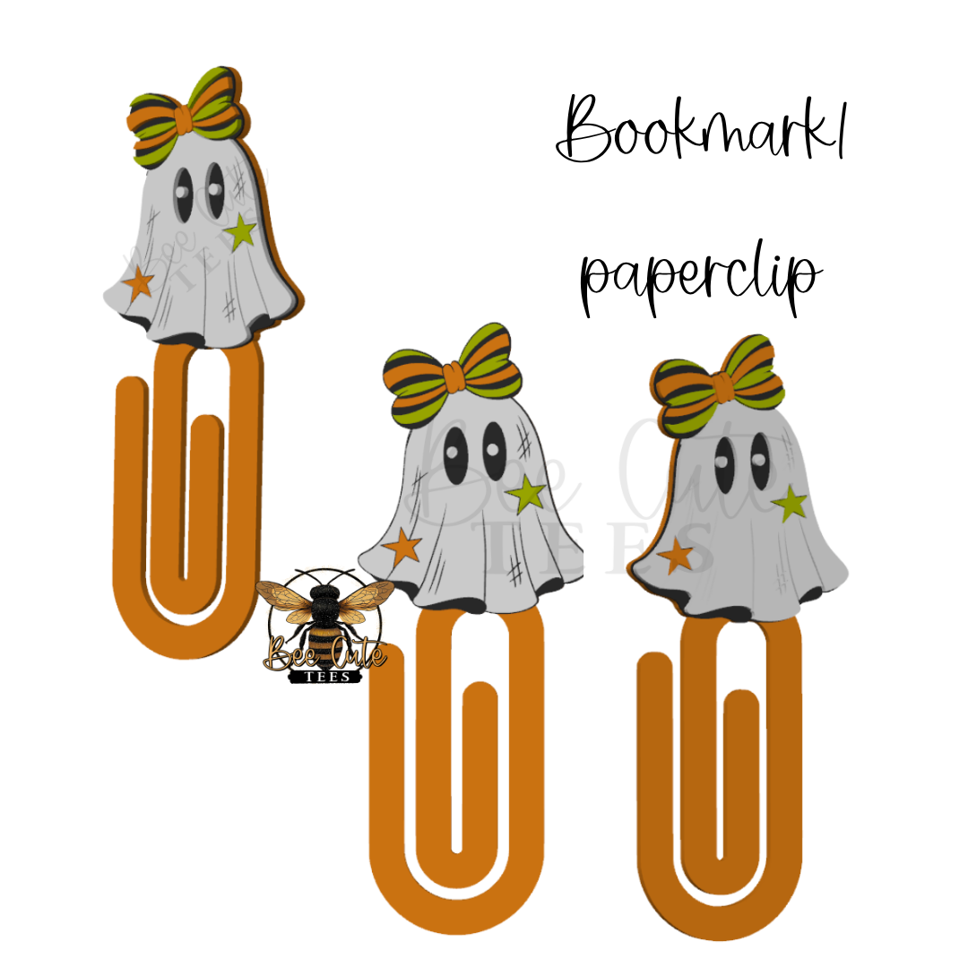 Three Halloween-themed paperclip bookmarks featuring ghost cutouts with green and orange striped bows, black eyes, and small orange stars, displayed on a white background with the text 'Bookmark paperclip' and a bee logo.
