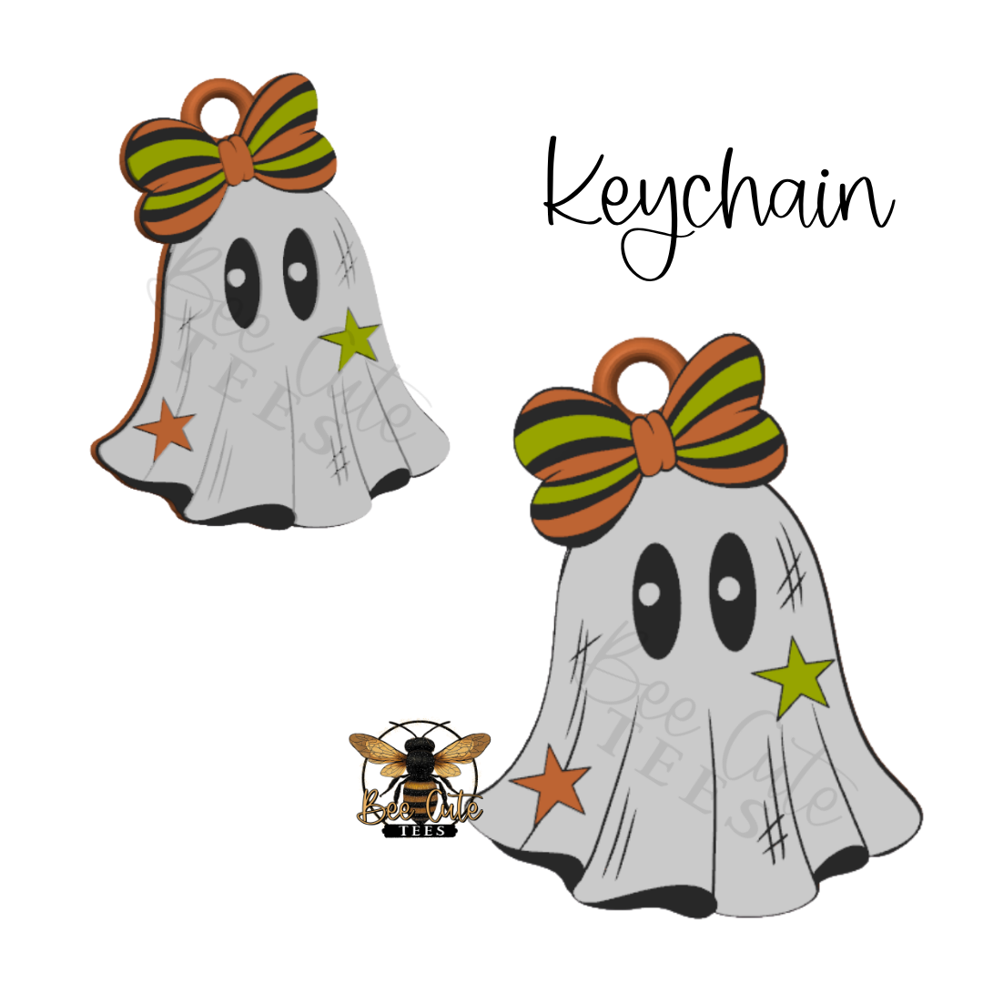 A Halloween-themed keychain featuring a cute ghost charm with a striped orange and green bow, and star accents, shown on a white background with a bee logo and the word 'Keychain'.