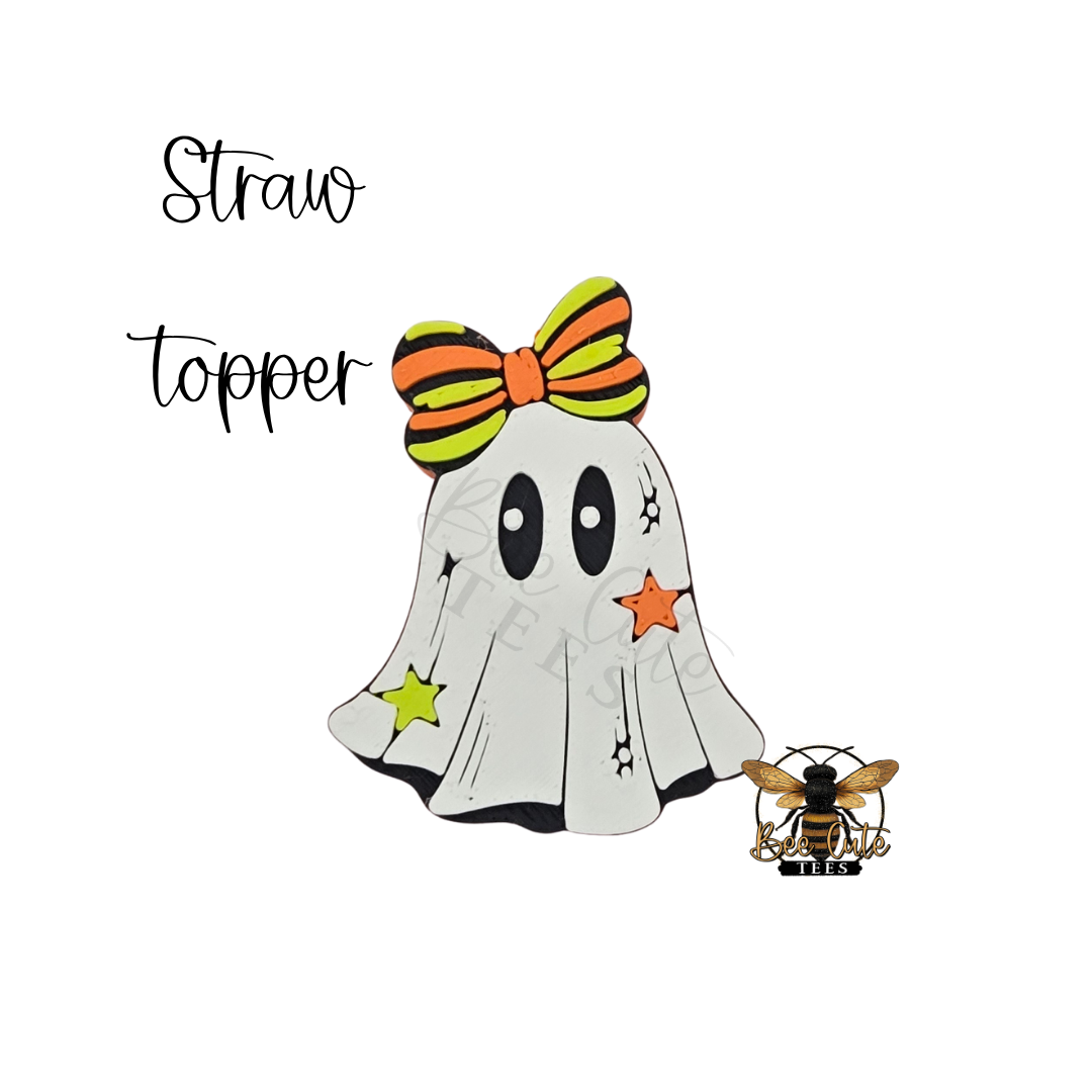 A Halloween-themed ghost topper design on a white background, featuring a white ghost with black eyes, an orange and black striped bow, star accents, and a small bee illustration. The text 'Straw topper' appears above.