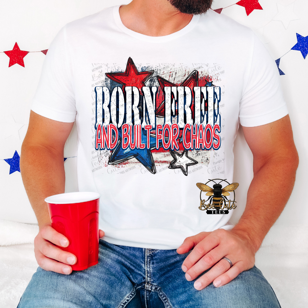 A person wearing a white short-sleeved t-shirt with a graphic that says 'BORNE FREE AND BUILT FOR CHAOS' along with images of stars and a logo, holding a red cup.