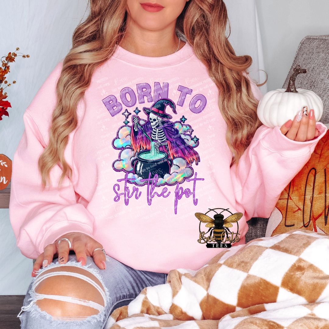 Person wearing a pink sweatshirt with a Halloween-themed design, sitting on a couch.