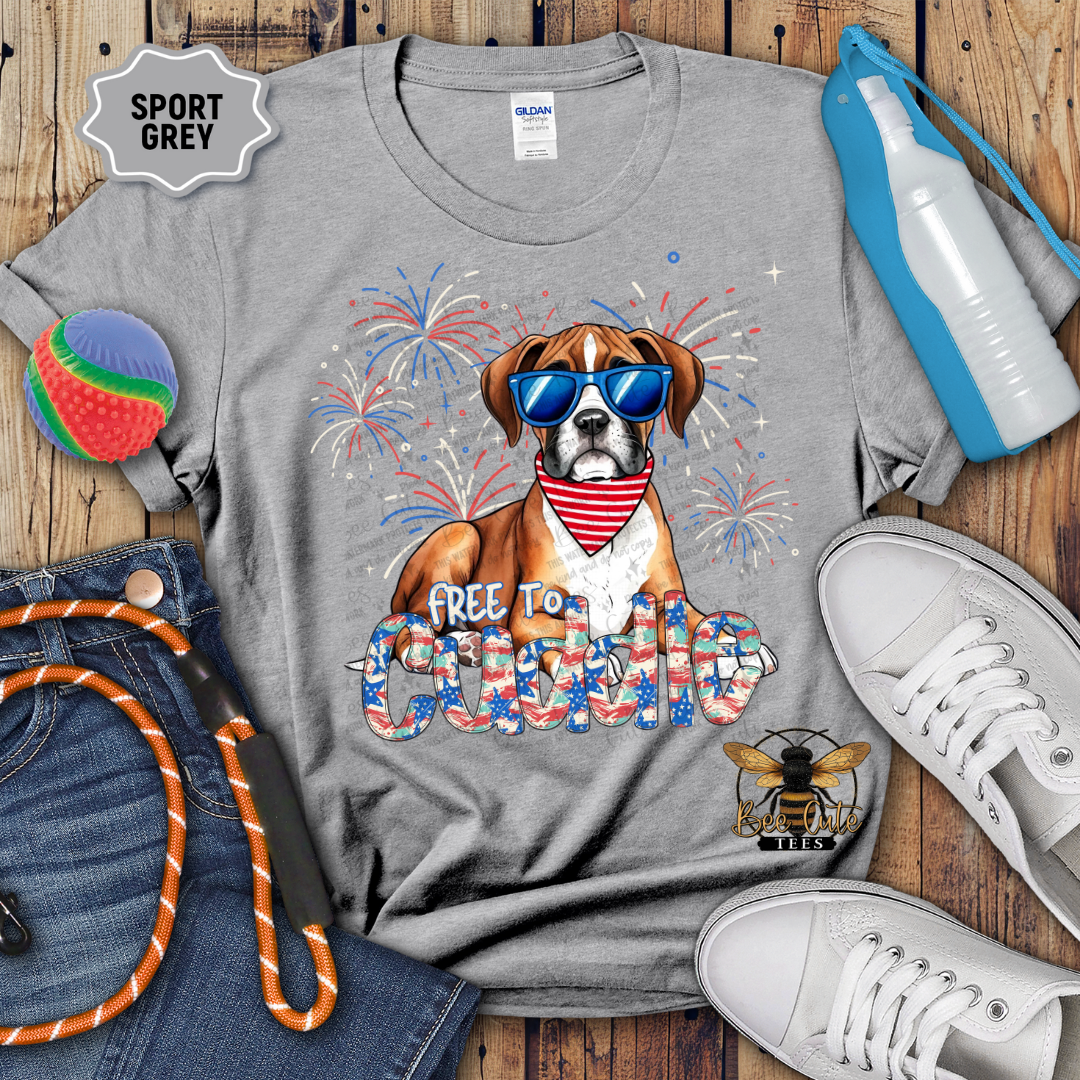 Gray t-shirt with a dog graphic and text, surrounded by casual items on a wooden surface.