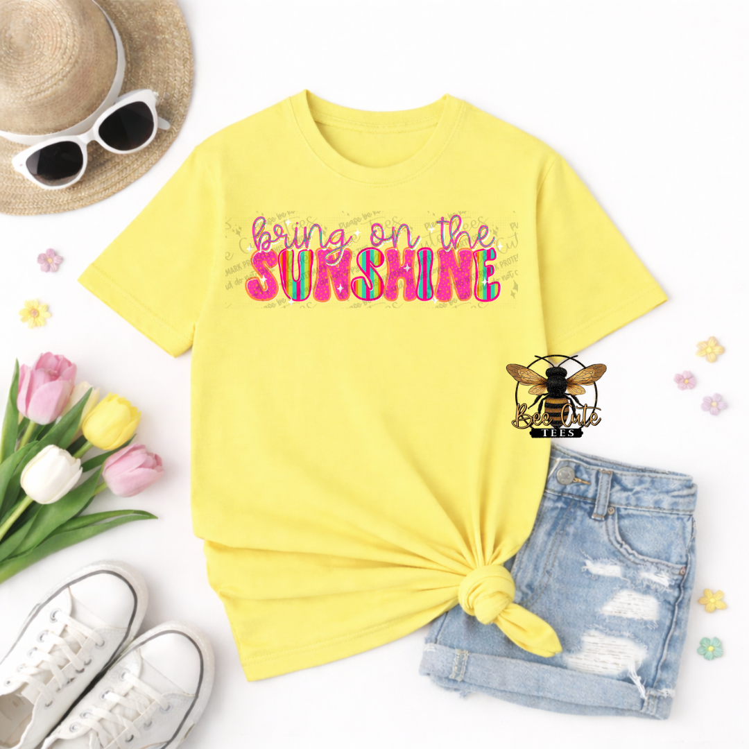 Yellow t-shirt with 'bring on the sunshine' text, sunglasses, tulips, and shorts on a white background