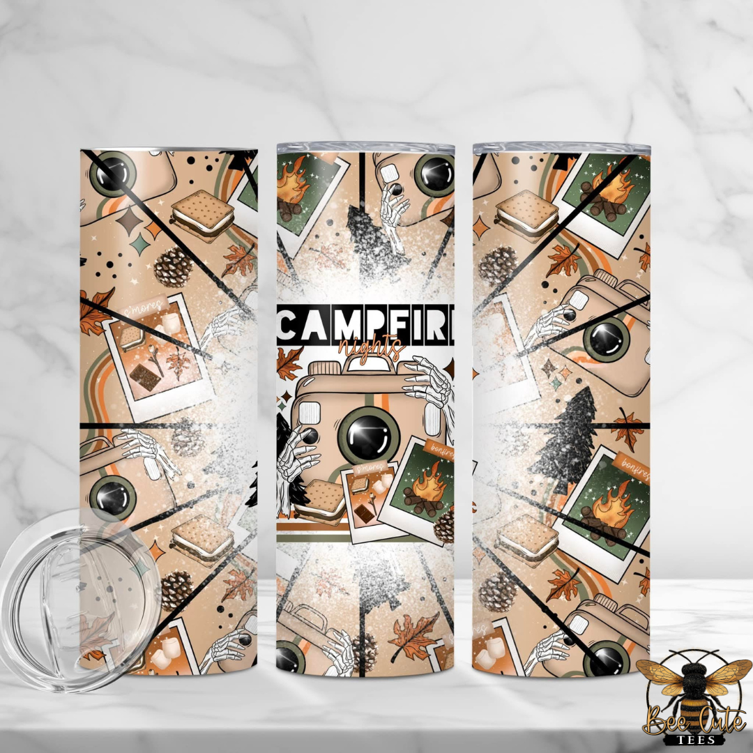 Three insulated tumblers with a beige and brown 'CAMPFIRE' summer camp theme print, shown on a white marble background with a clear lid in the foreground.