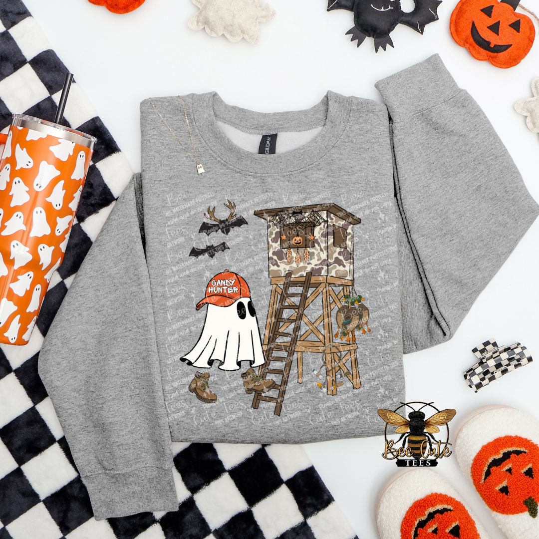 Gray sweatshirt with Halloween-themed design on a checkered background with pumpkins and ghosts.