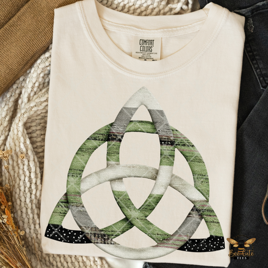 Folded white t-shirt with green and gray knot design on a textured surface.