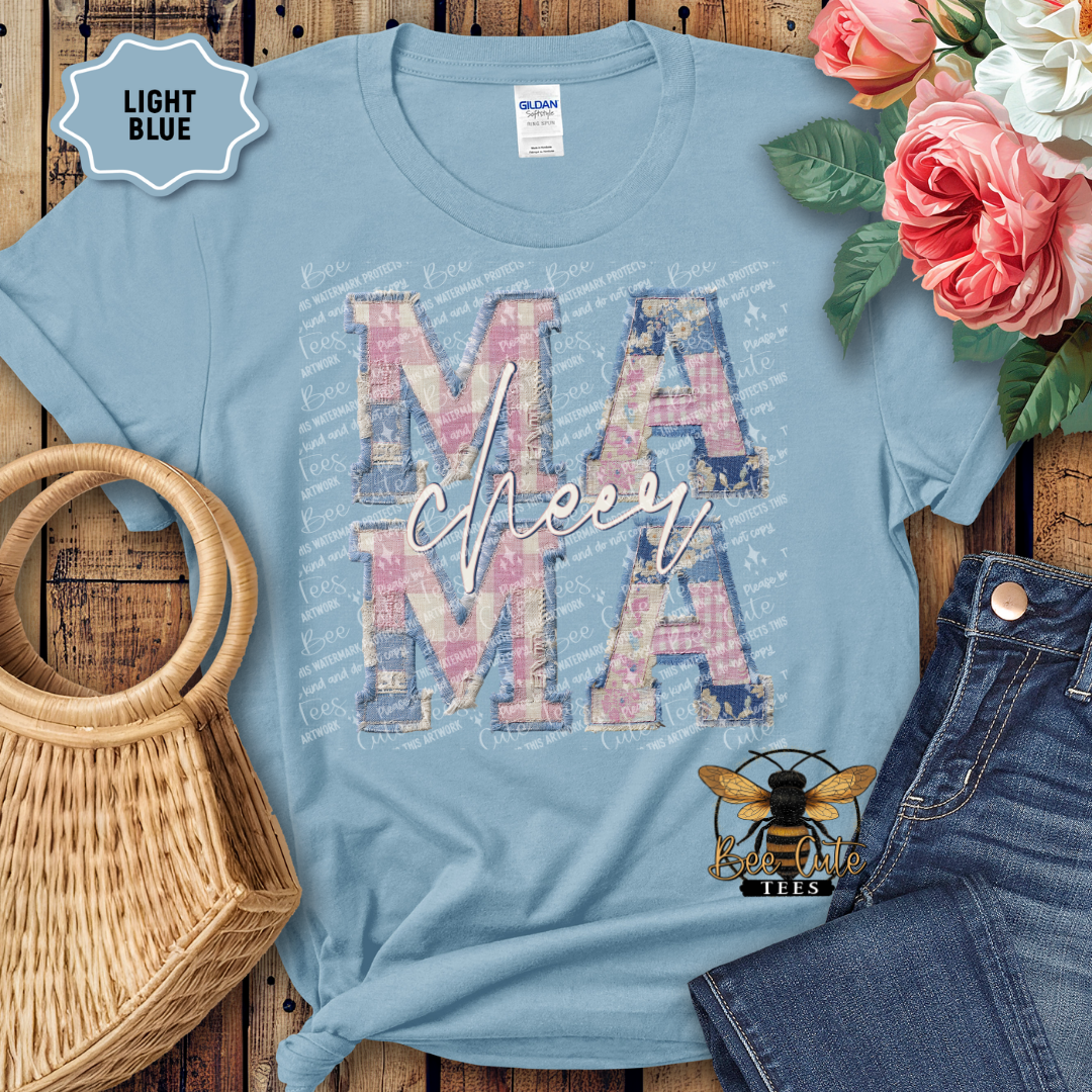 Light blue t-shirt with 'MAMA' design, surrounded by flowers and denim jeans on a wooden surface.
