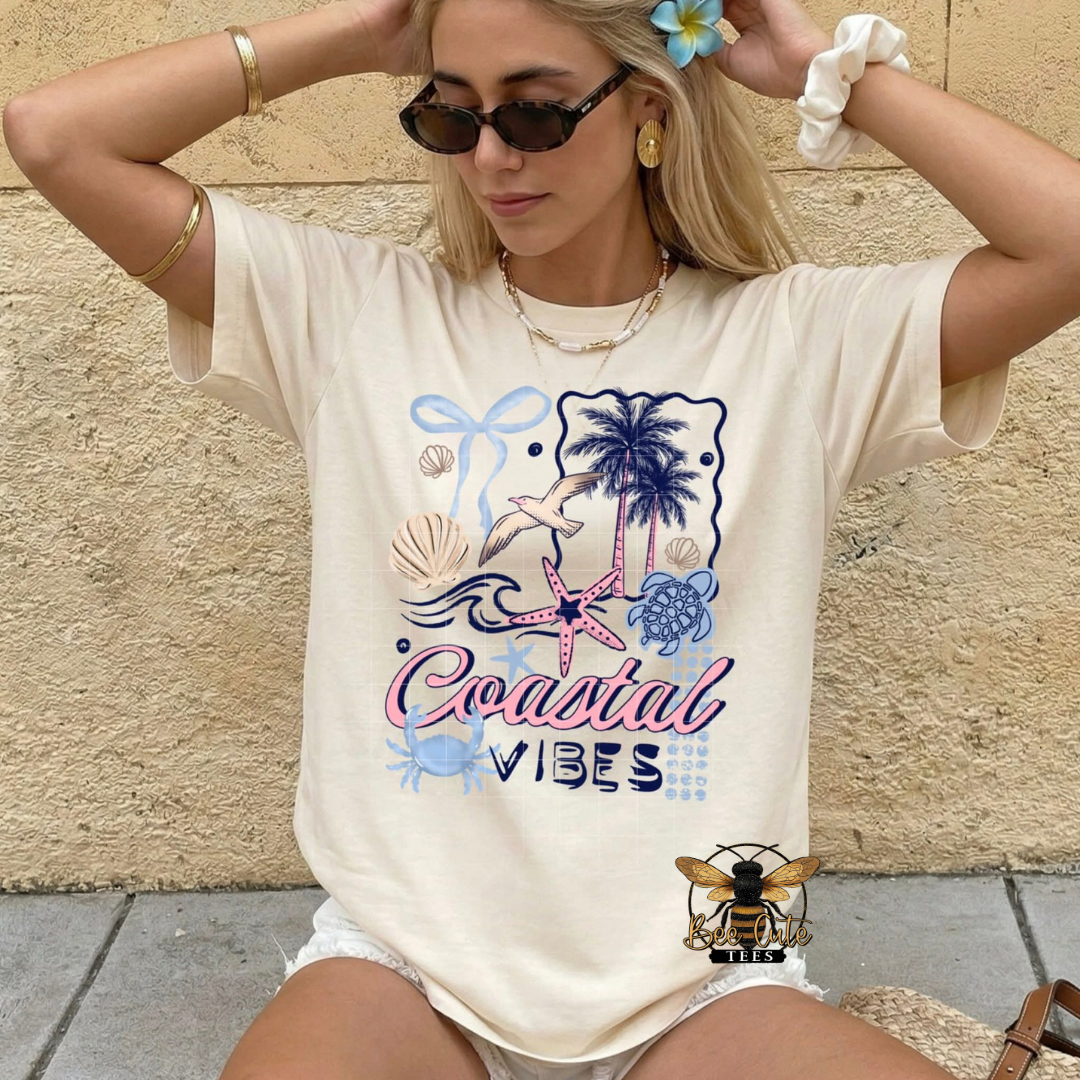 Woman wearing a 'Coastal Vibes' t-shirt with beach-themed graphics against a stone wall.