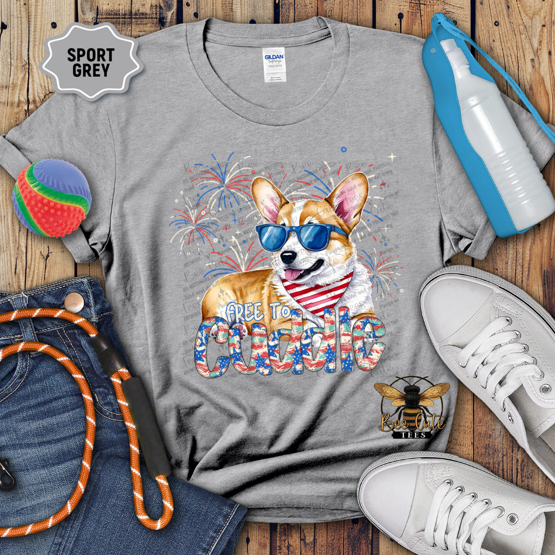 Gray t-shirt with a dog graphic and 'Free to Cuddle' text on a wooden surface with accessories.