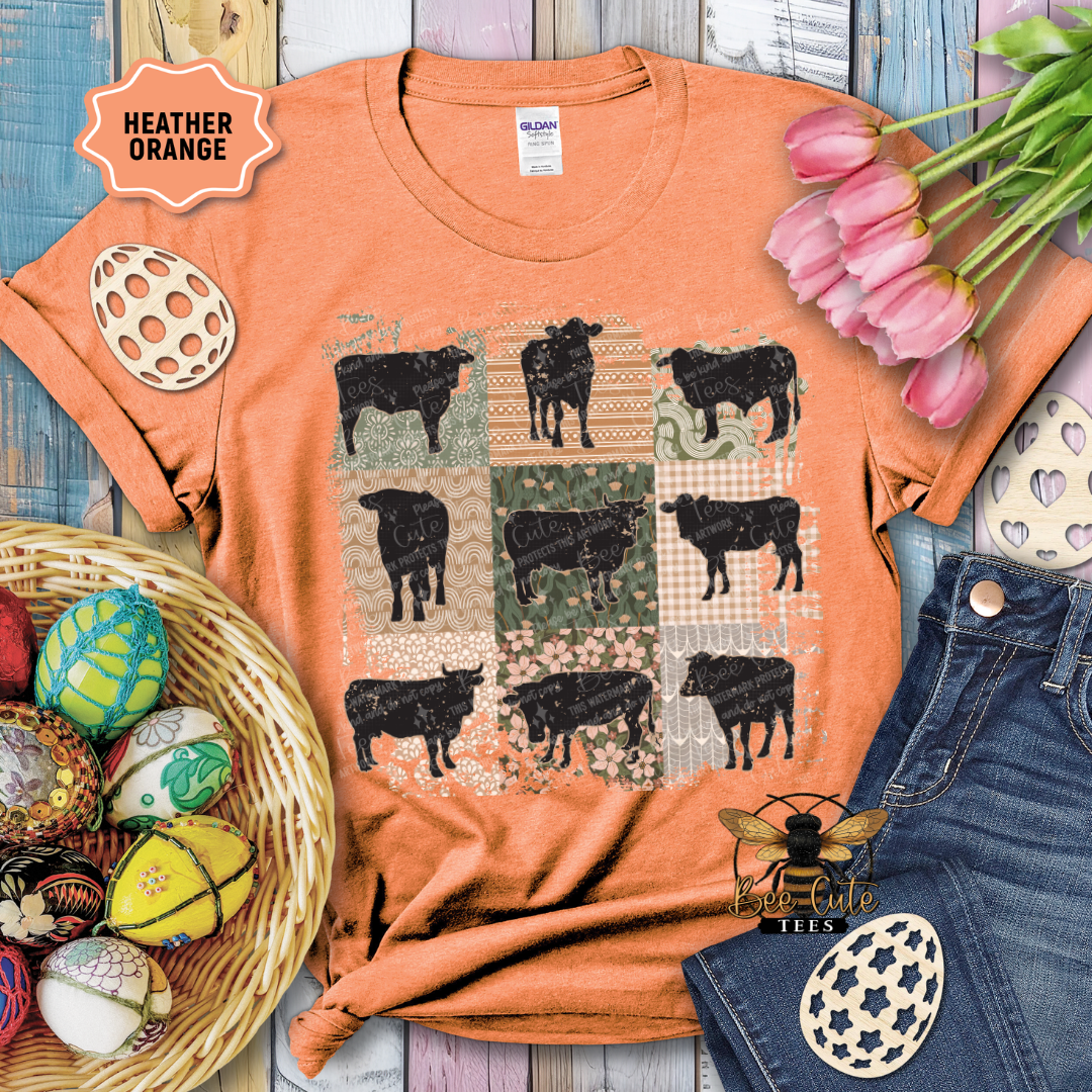 Orange t-shirt with black cow pattern, surrounded by decorative items on a wooden surface.
