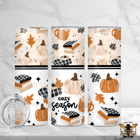 Three insulated tumblers with a fall-themed pattern of pumpkins, books, coffee cups, leaves, and stars, alongside a clear lid, displayed on a white marble background.