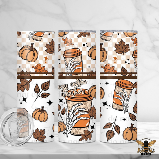 Three insulated tumblers with a fall-themed wrap design are displayed on a white marble surface. The design features pumpkins, autumn leaves, skeleton hands, and a coffee cup with the text 'my coffee is hotter'.