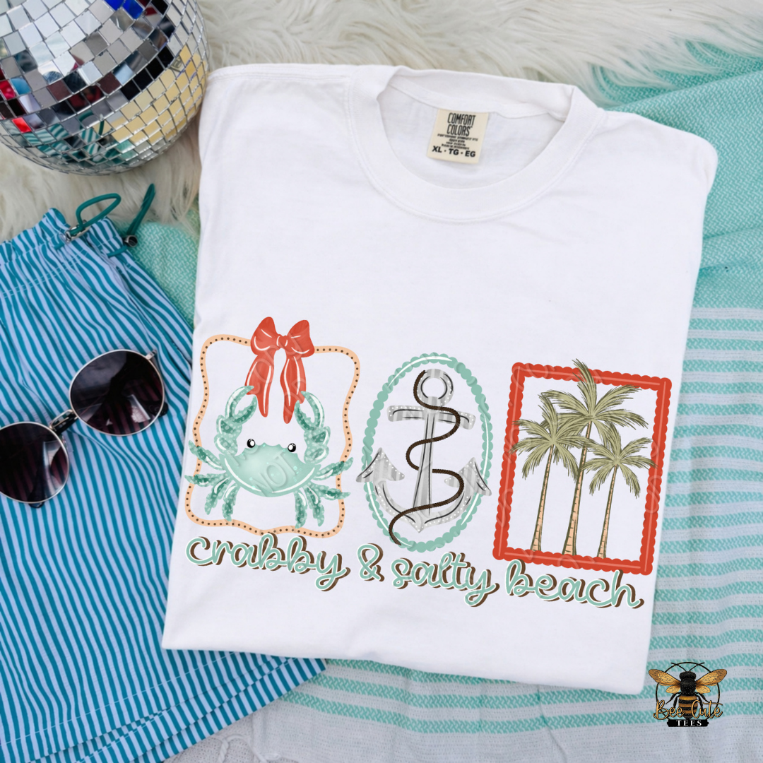 Folded white t-shirt with beach-themed design on a striped fabric background