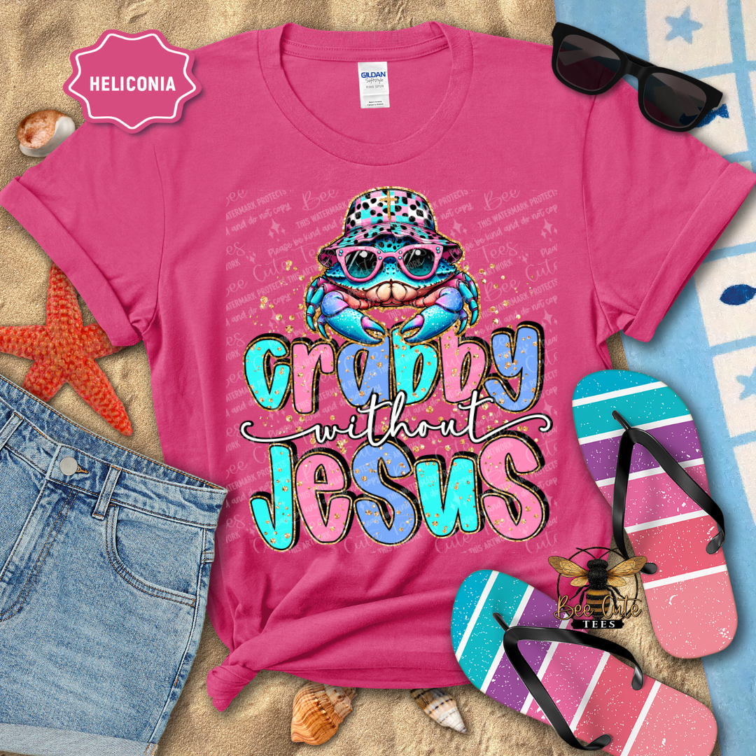 Pink t-shirt with colorful graphic and text, sunglasses, flip-flops, and beach items on a textured surface.