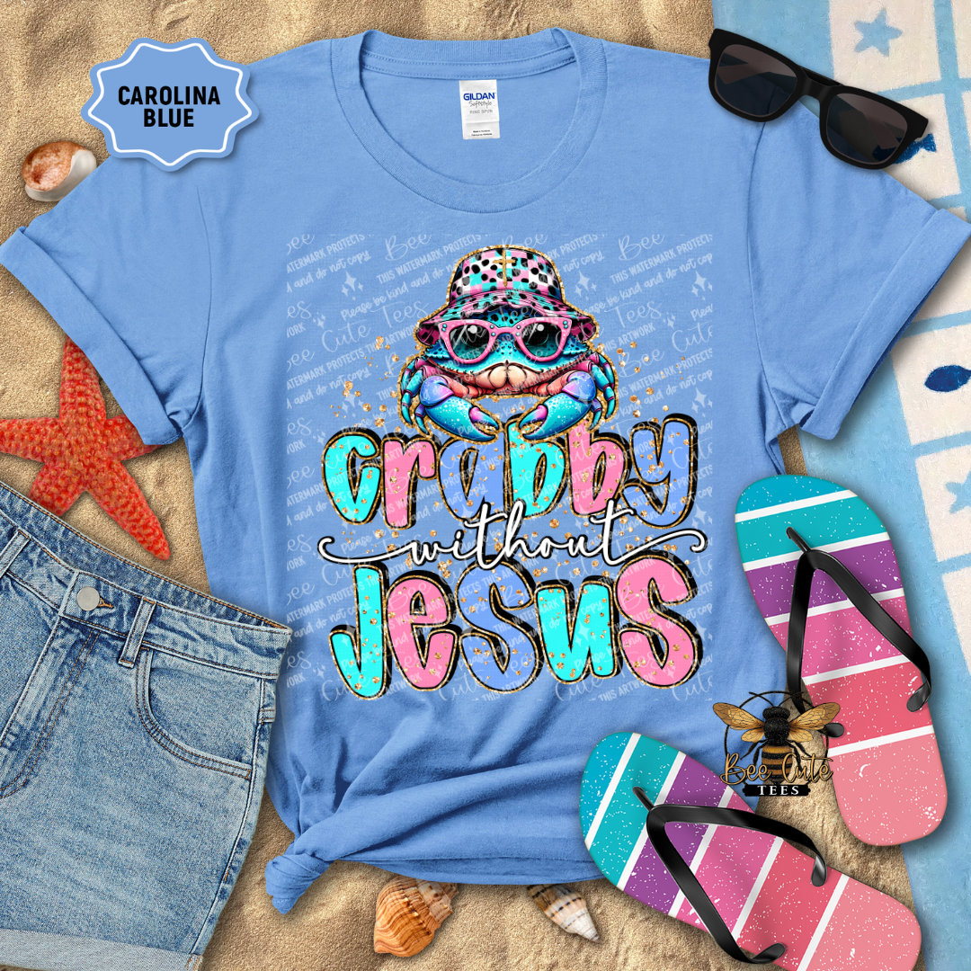Blue t-shirt with colorful graphic and text 'Crabby without Jesus' on a beach-themed background.