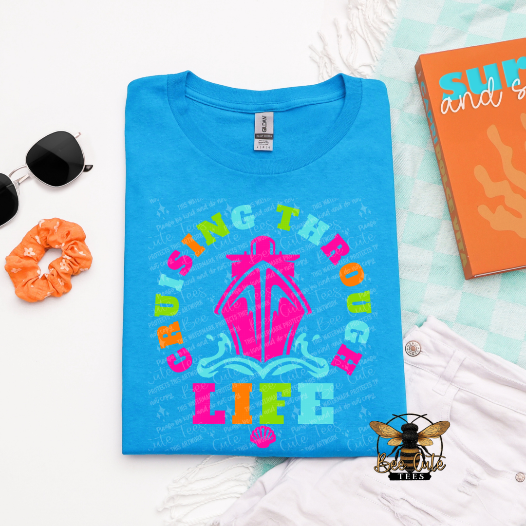 Blue t-shirt with colorful graphic and text 'Cruising the Open Sea Life' on a light blue background.
