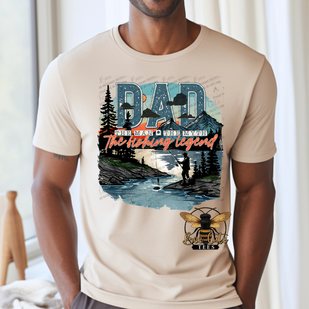Beige t-shirt with a graphic design featuring mountains, trees, and a fishing scene on a white background.