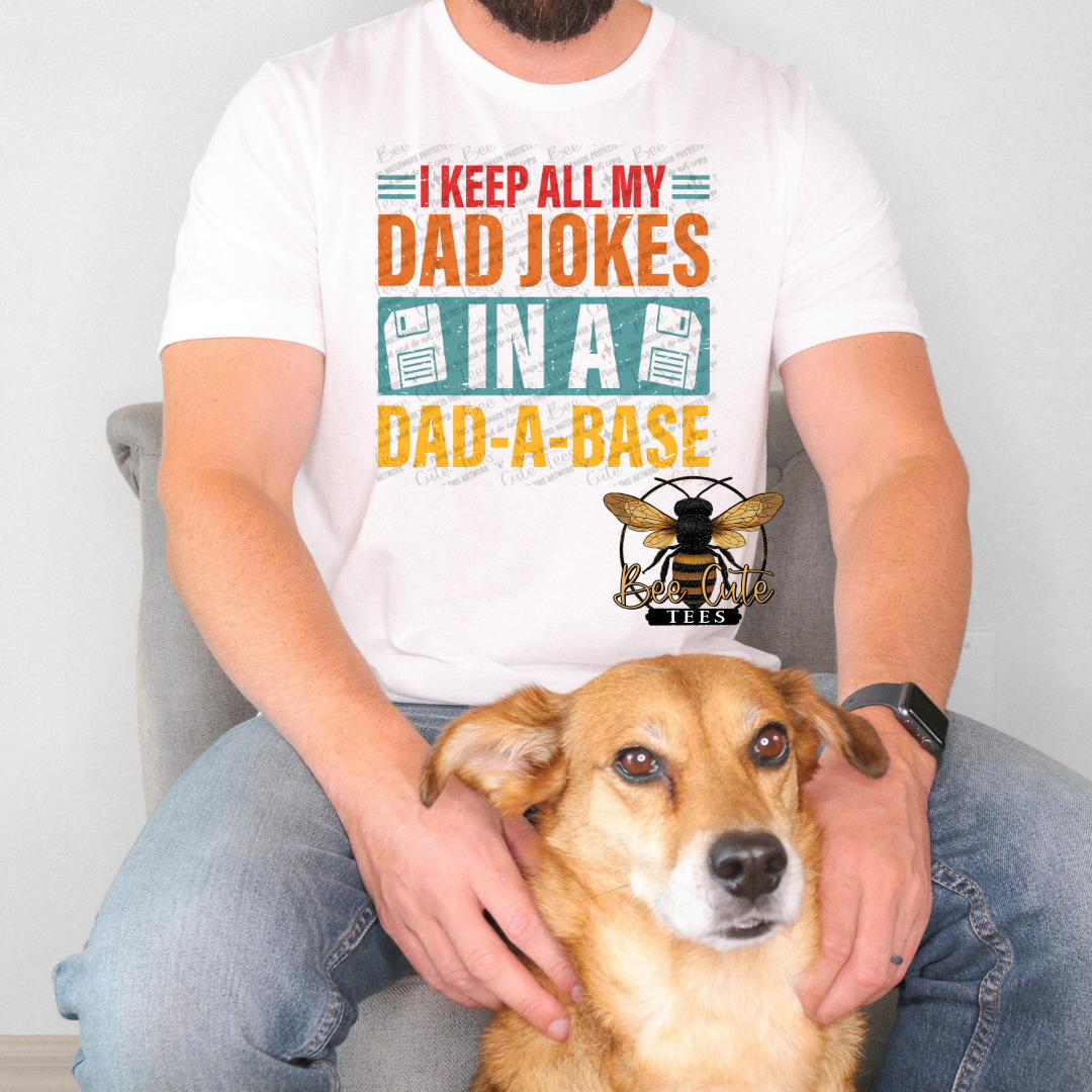 Person wearing a white t-shirt with a humorous design, sitting with a dog.