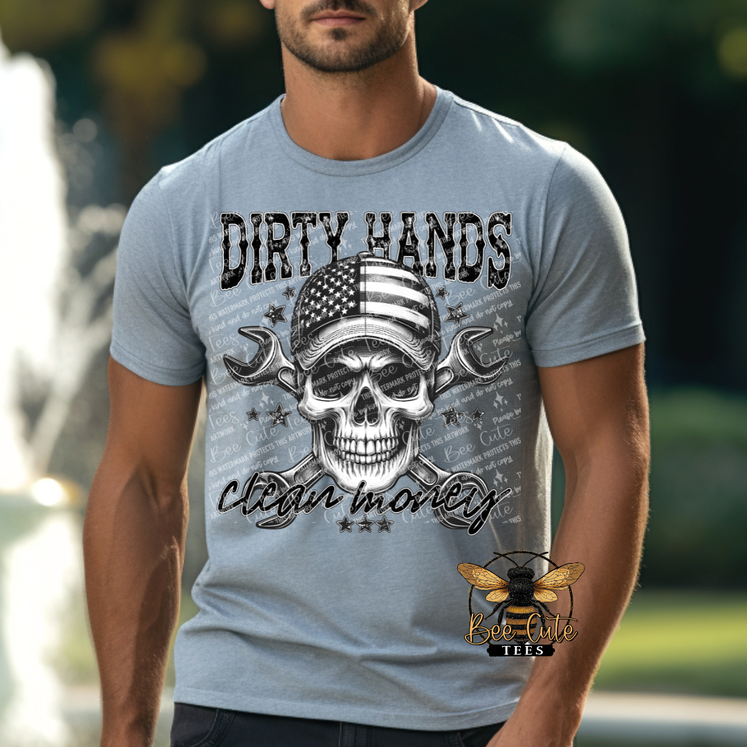 Man wearing a grey graphic tee featuring a skull with an American flag bandana and crossed wrenches, paired with the phrase “Dirty Hands, Clean Money” in bold distressed lettering.
