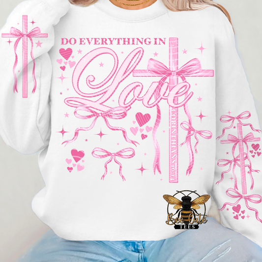 White sweatshirt with pink graphics and text 'Do Everything in Love' on a plain background
