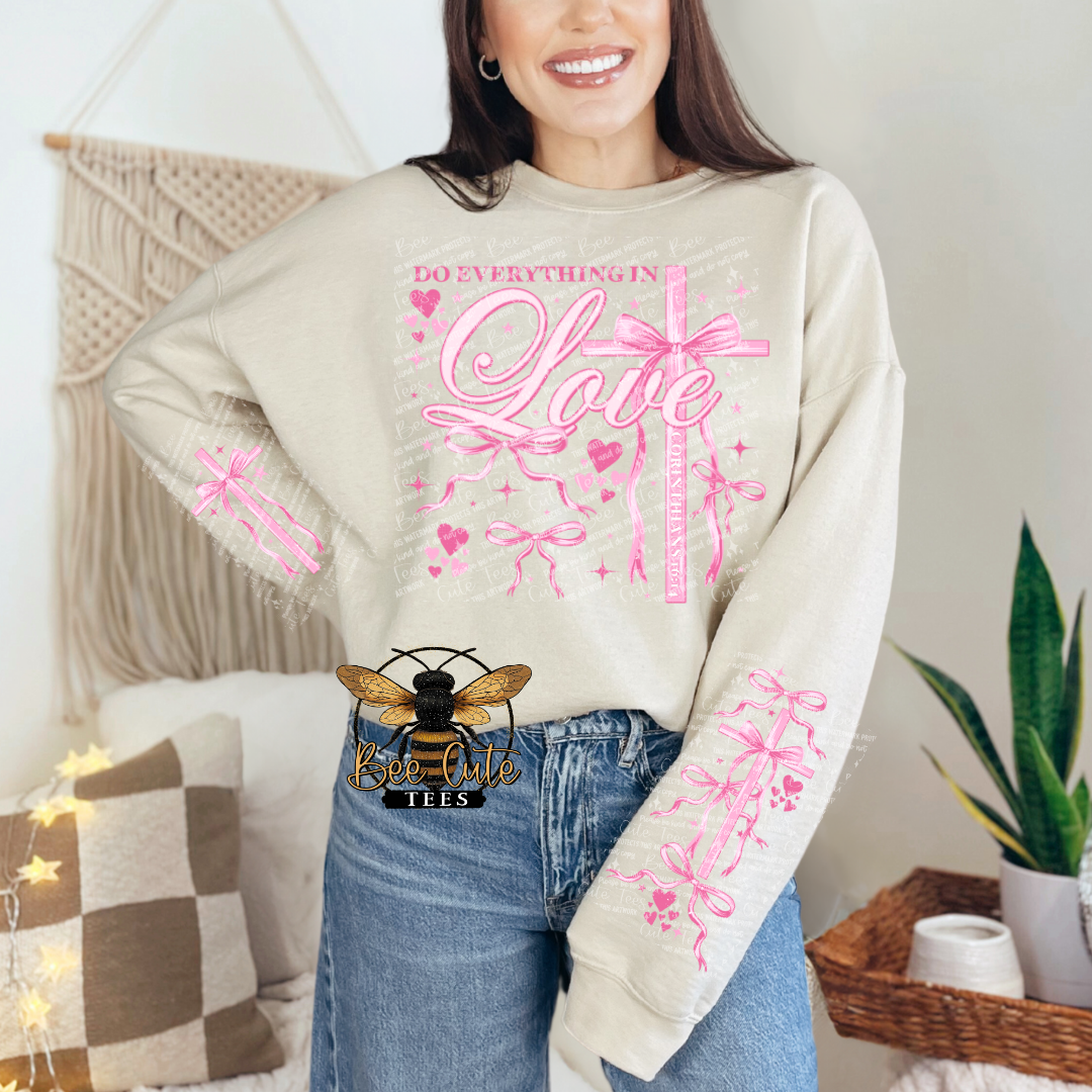 Woman wearing a beige sweatshirt with pink graphics and text, standing in a cozy room.