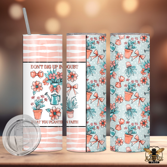 Set of three tumblers with floral and motivational designs on a wooden surface.