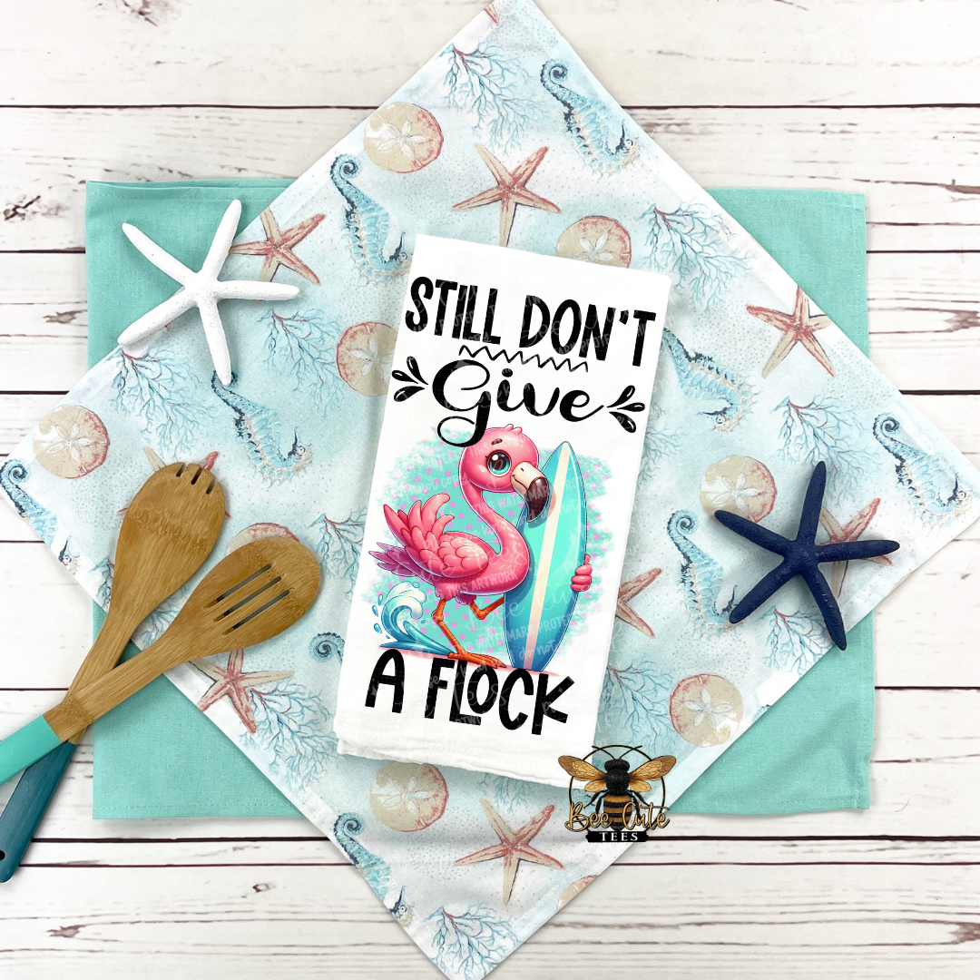 Flamingo-themed towel with motivational quote on a wooden surface with starfish and a spoon.