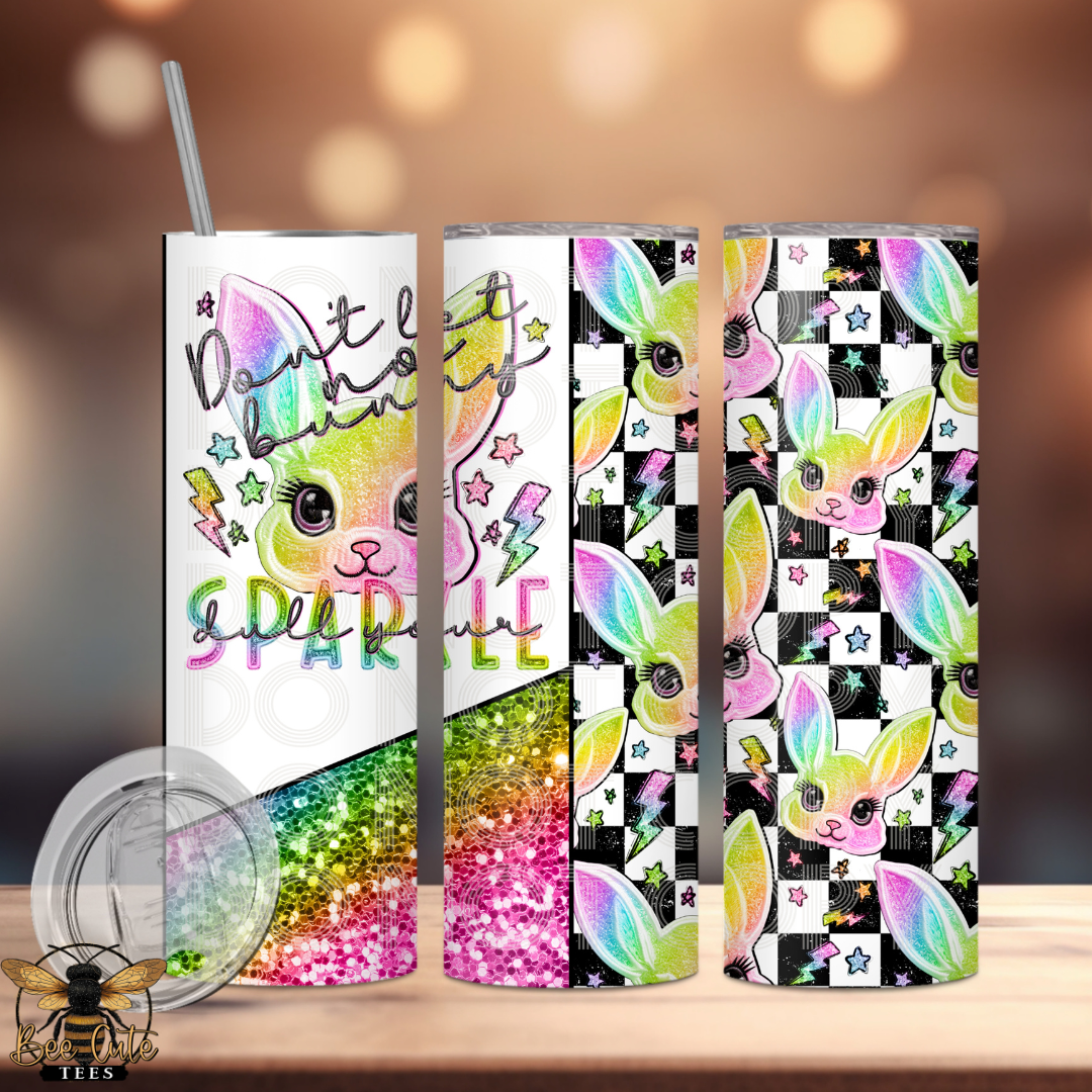 Set of colorful tumblers with bunny designs and text on a wooden surface.