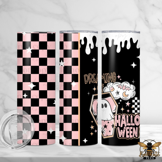 Three slim tumblers with Halloween-themed designs displayed on a white marble surface. The designs include a pink and black checkerboard pattern, a black background with white dripping paint and a ghost illustration, and a black background with a pink and white checkerboard pattern and the words 'HALLOWEEN'.