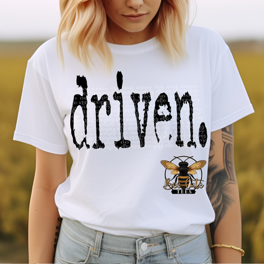 Person wearing a white t-shirt with 'driven' text and a bee logo.