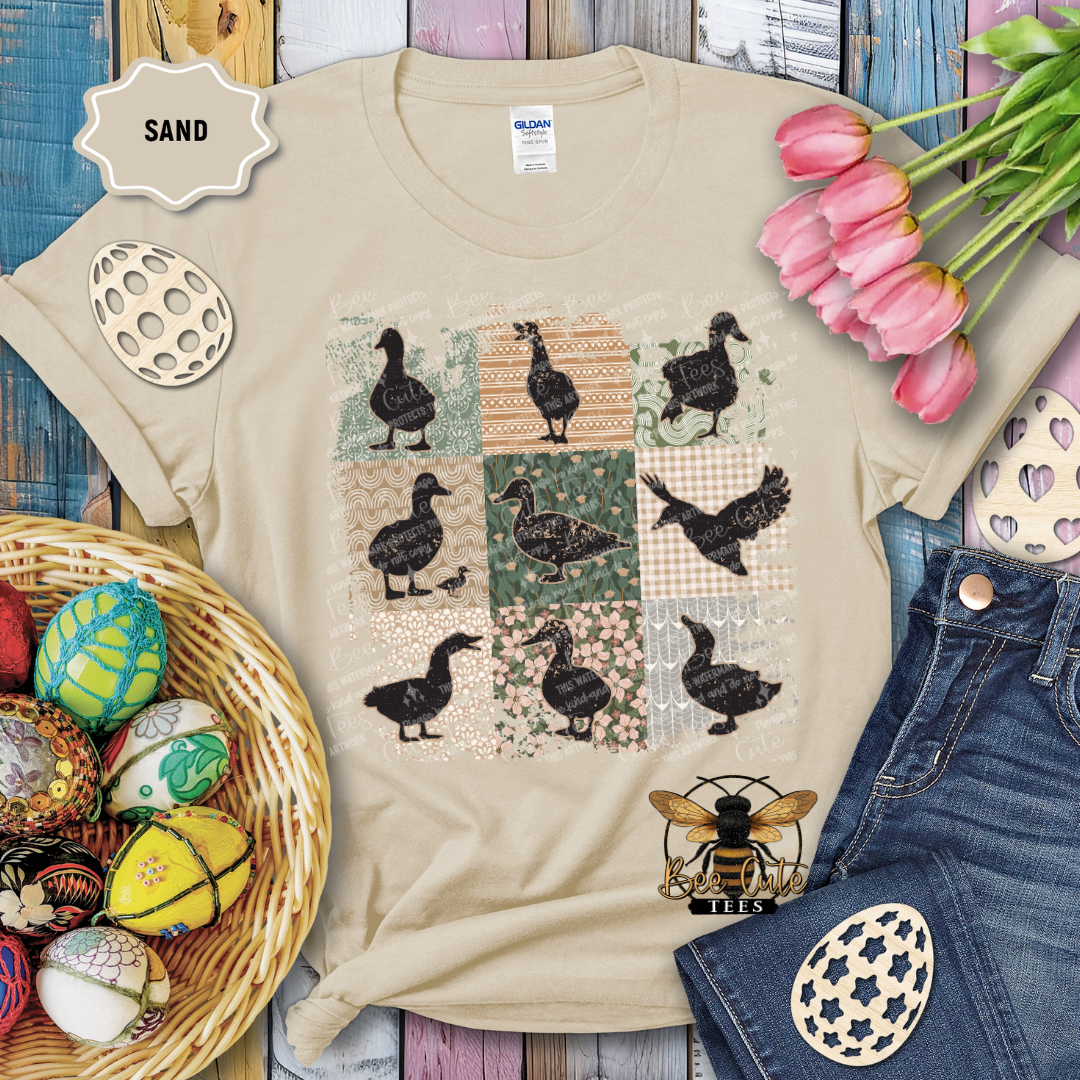 Beige t-shirt with duck pattern, surrounded by Easter decorations on a wooden surface.